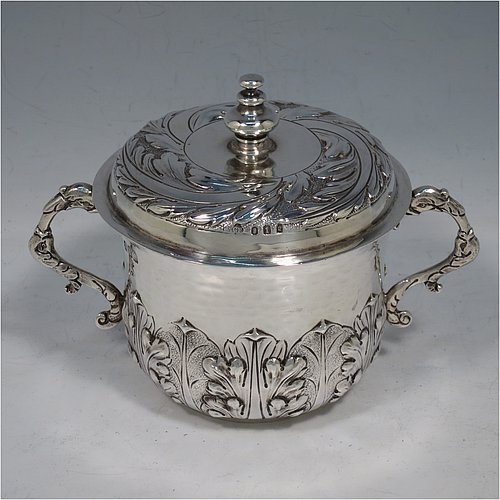 An Antique Edwardian Britannia Standard Silver porringer, having a round baluster body with a hand-hammered finish and hand-chased anthemion and floral decoration, a lift-off lid with matching floral work and a cast round finial, and two cast floral handles. Made by George Fox of London in 1906. The dimensions of this fine hand-made antique Britannia silver porringer and lid are height 11.5 cms (4.5 inches), spread across arms 16 cms (6.3 inches), and it weighs approx. 370g (12 troy ounces).    