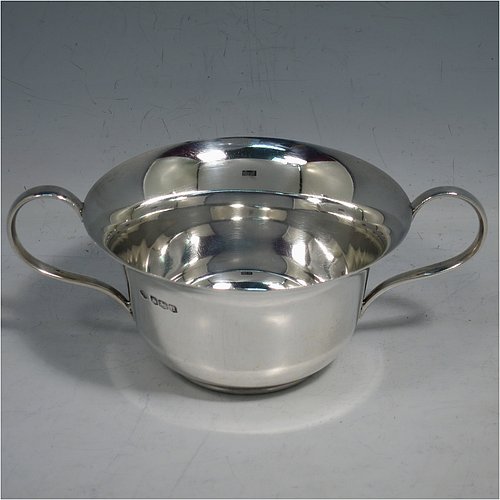 A Sterling Silver very simple porringer, having a plain round body, with two scroll side handles, and all sitting on a flat base. Made by William Hutton & Sons of Sheffield in 1918. The dimensions of this fine hand-made silver porringer are height 6 cms (2.3 inches), spread across arms 16 cms (6.3 inches), and it weighs approx. 140g (4.5 troy ounces).   