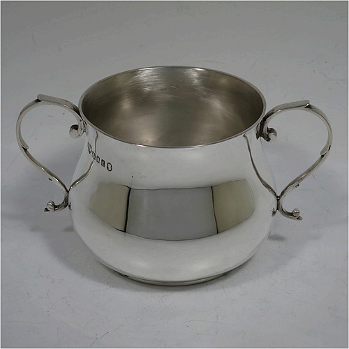 A very handsome Sterling Silver porringer, having a plain round bellied body, two scroll side handles, and sitting on a flat base. Made by Goldsmiths and Silversmiths of London in 1934. The dimensions of this fine hand-made silver porringer are height 7.5 cms (3 inches), spread across arms 13.5 cms (5.3 inches), and it weighs approx. 185g (6 troy ounces).    