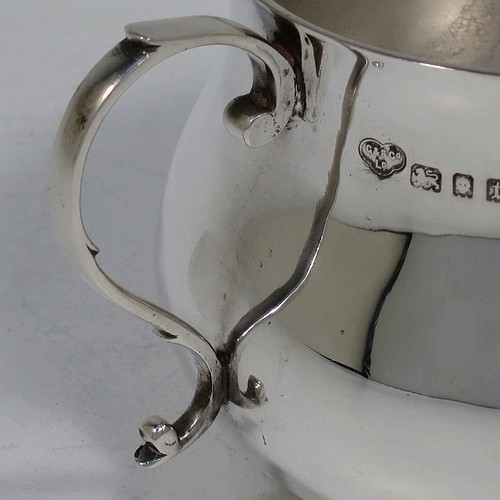 A very handsome Sterling Silver porringer, having a plain round bellied body, two scroll side handles, and sitting on a flat base. Made by Goldsmiths and Silversmiths of London in 1934. The dimensions of this fine hand-made silver porringer are height 7.5 cms (3 inches), spread across arms 13.5 cms (5.3 inches), and it weighs approx. 185g (6 troy ounces).    