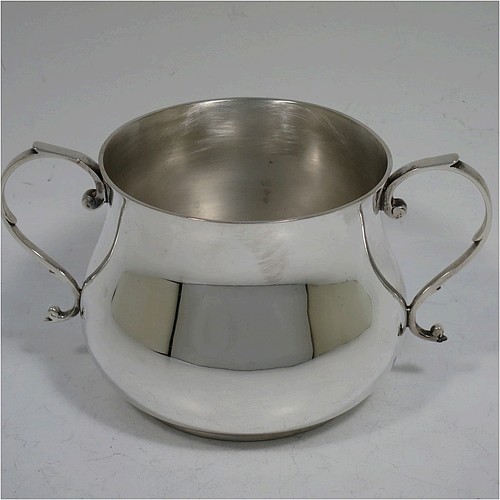 A very handsome Sterling Silver porringer, having a plain round bellied body, two scroll side handles, and sitting on a flat base. Made by Goldsmiths and Silversmiths of London in 1934. The dimensions of this fine hand-made silver porringer are height 7.5 cms (3 inches), spread across arms 13.5 cms (5.3 inches), and it weighs approx. 185g (6 troy ounces).    