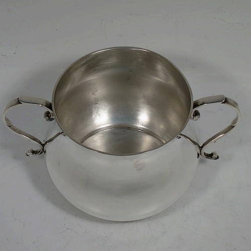 A very handsome Sterling Silver porringer, having a plain round bellied body, two scroll side handles, and sitting on a flat base. Made by Goldsmiths and Silversmiths of London in 1934. The dimensions of this fine hand-made silver porringer are height 7.5 cms (3 inches), spread across arms 13.5 cms (5.3 inches), and it weighs approx. 185g (6 troy ounces).    