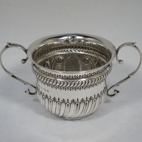 A very handsome Antique Sterling Silver porringer, having a round bellied body with hand-chased fluted and scroll decoration, with a vacant oval cartouche on one side, two scroll side-handles, and sitting on a flat base. Made by S. Blanckensee and Son Lt., of Birmingham in 1919. The dimensions of this fine hand-made antique silver porringer are height 8 cms (3.25 inches), spread across handles 16.5 cms (6.5 inches), and it weighs approx. 200g (6.5 troy ounces).   