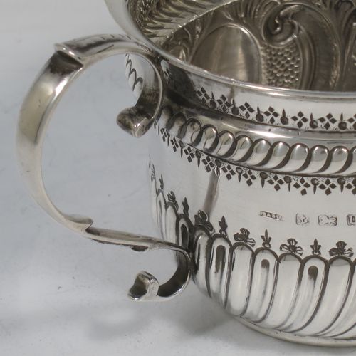 A very handsome Antique Sterling Silver porringer, having a round bellied body with hand-chased fluted and scroll decoration, with a vacant oval cartouche on one side, two scroll side-handles, and sitting on a flat base. Made by S. Blanckensee and Son Lt., of Birmingham in 1919. The dimensions of this fine hand-made antique silver porringer are height 8 cms (3.25 inches), spread across handles 16.5 cms (6.5 inches), and it weighs approx. 200g (6.5 troy ounces).   