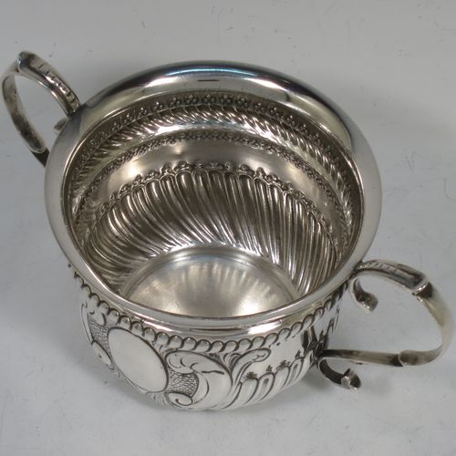 A very handsome Antique Sterling Silver porringer, having a round bellied body with hand-chased fluted and scroll decoration, with a vacant oval cartouche on one side, two scroll side-handles, and sitting on a flat base. Made by S. Blanckensee and Son Lt., of Birmingham in 1919. The dimensions of this fine hand-made antique silver porringer are height 8 cms (3.25 inches), spread across handles 16.5 cms (6.5 inches), and it weighs approx. 200g (6.5 troy ounces).   