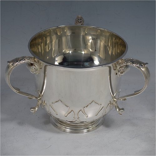 A heavy Sterling Silver three-handled porringer or loving cup, having a round body with tucked under belly and applied cut-card work, three cast scroll side-handles, and sitting on a pedestal foot. Made by Goldsmiths & Silversmiths of London in 1937. The dimensions of this fine hand-made silver loving cup or porringer are height 9.5 cms (3.75 inches), diameter 10 cms (4 inches), and it weighs approx. 417g (13.5 troy ounces).   