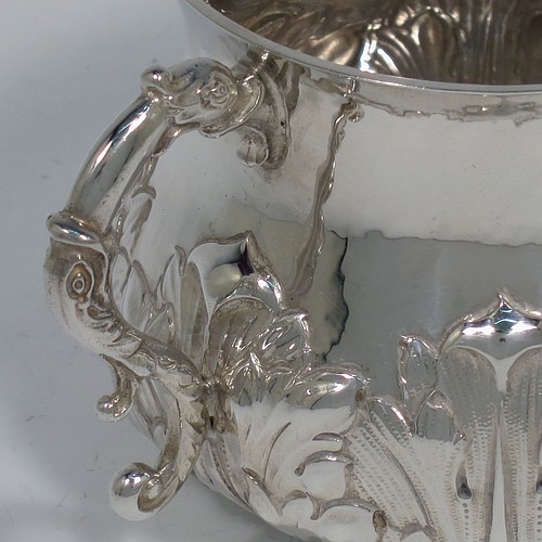 A heavy Sterling Silver porringer, having a round bellied body with a slight hand-hammered finish and hand-chased anthemion and floral decoration, and two cast side-handles with stylised dolphin heads. Made by Robert Comyns of London in 1931. The dimensions of this fine hand-made silver porringer are height 7 cms (2.75 inches), spread across arms 14 cms (5.5 inches), and it weighs approx. 247g (8 troy ounces).    