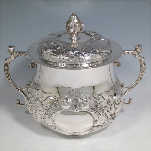 An Antique Victorian Sterling Silver porringer and cover, having a round baluster body, with hand-chased floral decoration, two cast figural scroll side handles, a pull-off cover with cast finial, and all sitting on a flat base. Made by Carringtons & Co., of London in 1906. The dimensions of this fine hand-made silver porringer are height 19 cms (7.5 inches), spread across arms 23.5 cms (9.25 inches), and it weighs approx. 885g (28.5 troy ounces).   