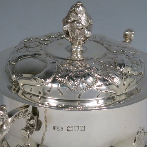 An Antique Victorian Sterling Silver porringer and cover, having a round baluster body, with hand-chased floral decoration, two cast figural scroll side handles, a pull-off cover with cast finial, and all sitting on a flat base. Made by Carringtons & Co., of London in 1906. The dimensions of this fine hand-made silver porringer are height 19 cms (7.5 inches), spread across arms 23.5 cms (9.25 inches), and it weighs approx. 885g (28.5 troy ounces).   