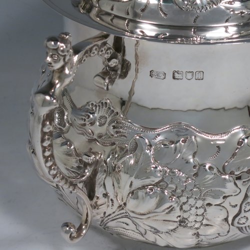 An Antique Victorian Sterling Silver porringer and cover, having a round baluster body, with hand-chased floral decoration, two cast figural scroll side handles, a pull-off cover with cast finial, and all sitting on a flat base. Made by Carringtons & Co., of London in 1906. The dimensions of this fine hand-made silver porringer are height 19 cms (7.5 inches), spread across arms 23.5 cms (9.25 inches), and it weighs approx. 885g (28.5 troy ounces).   