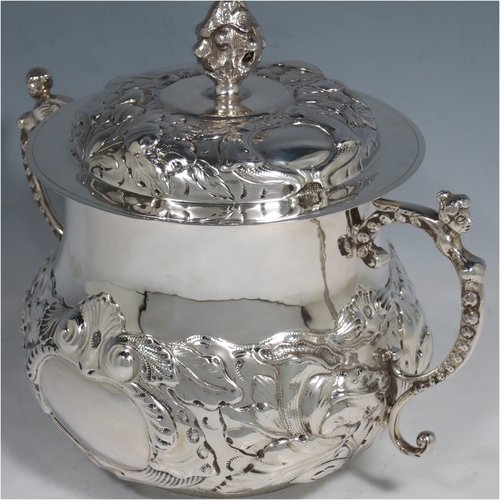 An Antique Victorian Sterling Silver porringer and cover, having a round baluster body, with hand-chased floral decoration, two cast figural scroll side handles, a pull-off cover with cast finial, and all sitting on a flat base. Made by Carringtons & Co., of London in 1906. The dimensions of this fine hand-made silver porringer are height 19 cms (7.5 inches), spread across arms 23.5 cms (9.25 inches), and it weighs approx. 885g (28.5 troy ounces).   