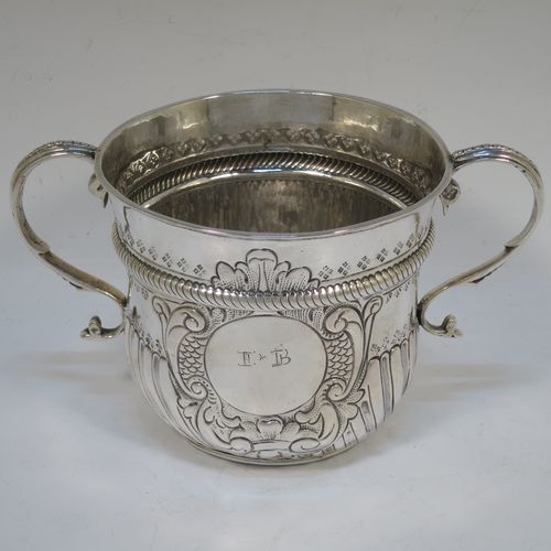 A very handsome Antique Queen Anne Britannia Standard Silver porringer, having a round bellied body with hand-chased fluted and scroll decoration, with a round cartouche on one side, two scroll side-handles, and sitting on a flat base. Made by Timothy Ley of London in 1714. The dimensions of this fine hand-made antique Britannia silver porringer are height 11 cms (4.25 inches), spread across handles 18 cms (7 inches), and it weighs approx. 284g (9 troy ounces). Please note that this item has an engraved contemporaneous set of initials in the cartouche.