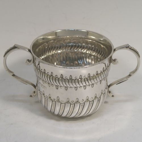 A very handsome Antique Edwardian Sterling Silver porringer, having a round bellied body with bands of hand-chased fluted decoration, two scroll side-handles, and sitting on a flat base. This elegant silver poringer was made by D. and J. Welby of London in 1906. The dimensions of this fine hand-made antique silver porringer are height 7 cms (2.75 inches), spread across handles 14 cms (5.5 inches), and it weighs approx. 182g (5.9 troy ounces).  