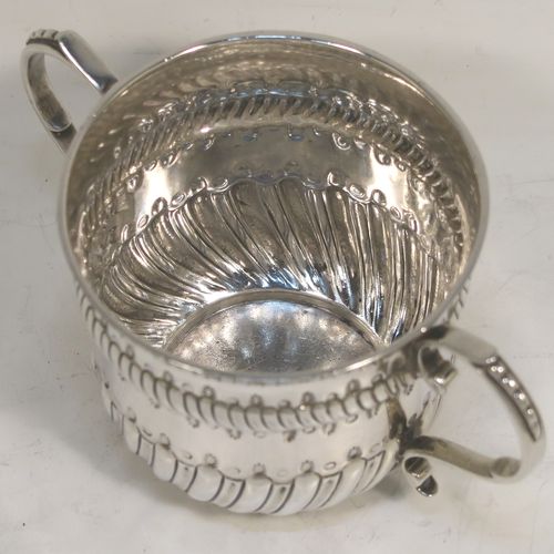 A very handsome Antique Edwardian Sterling Silver porringer, having a round bellied body with bands of hand-chased fluted decoration, two scroll side-handles, and sitting on a flat base. This elegant silver poringer was made by D. and J. Welby of London in 1906. The dimensions of this fine hand-made antique silver porringer are height 7 cms (2.75 inches), spread across handles 14 cms (5.5 inches), and it weighs approx. 182g (5.9 troy ounces).  