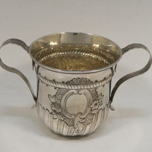 A very handsome Antique Georgian Sterling Silver porringer, having a round bellied body with hand-chased fluted and scroll decoration, with an oval vacant cartouche on one side, two scroll side-handles with leaf decoration, a lemon gold gilt interior, and sitting on a flat base. This beautiful antique silver porringer was made by Thomas Pitts I (poss.) of London in 1760. The dimensions of this fine hand-made antique silver porringer are height 10 cms (4 inches), spread across handles 16.5 cms (6.5 inches), and it weighs approx. 225g (7.3 troy ounces).   