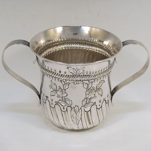 A beautiful Antique Georgian Sterling Silver porringer, having a round bellied body with hand-chased fluted and scroll decoration, with a vacant cartouche on one side surrounded by hand-chased floral decoration, two scroll and reeded side-handles, and all sitting on a flat base. This pretty antique silver poringer was made by William Cattell of London in 1778. The dimensions of this fine hand-made antique silver porringer are height 11.5 cms (4.5 inches), spread across handles 19 cms (7.5 inches), and it weighs approx. 317g (10.2 troy ounces).   