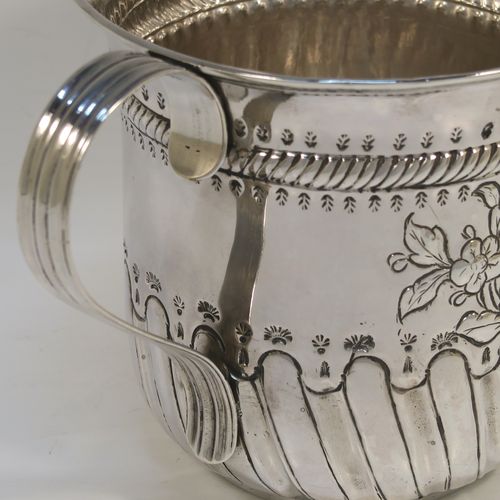 A beautiful Antique Georgian Sterling Silver porringer, having a round bellied body with hand-chased fluted and scroll decoration, with a vacant cartouche on one side surrounded by hand-chased floral decoration, two scroll and reeded side-handles, and all sitting on a flat base. This pretty antique silver poringer was made by William Cattell of London in 1778. The dimensions of this fine hand-made antique silver porringer are height 11.5 cms (4.5 inches), spread across handles 19 cms (7.5 inches), and it weighs approx. 317g (10.2 troy ounces).   