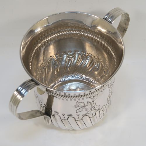 A beautiful Antique Georgian Sterling Silver porringer, having a round bellied body with hand-chased fluted and scroll decoration, with a vacant cartouche on one side surrounded by hand-chased floral decoration, two scroll and reeded side-handles, and all sitting on a flat base. This pretty antique silver poringer was made by William Cattell of London in 1778. The dimensions of this fine hand-made antique silver porringer are height 11.5 cms (4.5 inches), spread across handles 19 cms (7.5 inches), and it weighs approx. 317g (10.2 troy ounces).   