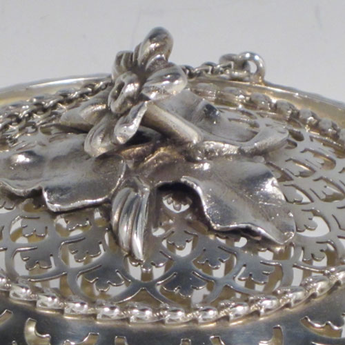 Antique Edwardian sterling silver pot pourri holder, having a round bellied hand-pierced body, a pull-off lid with cast floral finial, and an attached triple chain and hook. Made by Skinner and Co., of London in 1910. The dimensions of this fine hand-made silver pot-pourri holder are diameter 10 cms (4 inches), height 8.5 cms (3.25 inches), and it weighs approx. 204g (6.6 troy ounces).