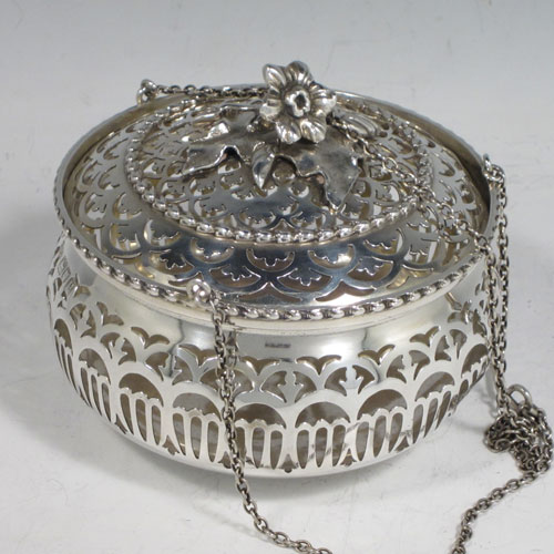 Antique Edwardian sterling silver pot pourri holder, having a round bellied hand-pierced body, a pull-off lid with cast floral finial, and an attached triple chain and hook. Made by Skinner and Co., of London in 1910. The dimensions of this fine hand-made silver pot-pourri holder are diameter 10 cms (4 inches), height 8.5 cms (3.25 inches), and it weighs approx. 204g (6.6 troy ounces).