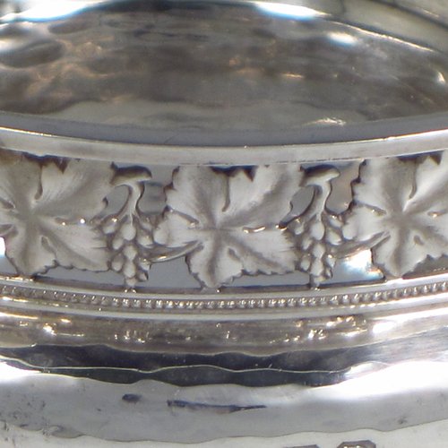 A Sterling silver Arts & Crafts style quaich, having a round baluster body with hand-hammered decoration, a hand-pierced grape-vine border, with two cast side-handles showing a scene with fox and tree, and all sitting on a flat base. Made by A. E. Jones of Birmingham in 1928. The dimensions of this fine hand-made silver Arts and Crafts quaich are diameter of body 12 cms (4.75 inches), height 4 cms (1.5 inches), and it weighs approx. 151g (4.9 troy ounces). 