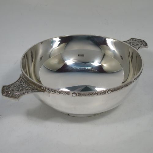 A very handsome and large Sterling Silver Celtic style Quaich, having a very plain round body, with two cast side handles in a Celtic or Cymmric style, a matching applied border, and sitting on a collet foot. This elegant silver Quaich was made by Wakely & Wheeler of London in 1990. The dimensions of this fine hand-made silver Celtic Quaich are diameter of body 16 cms (6.25 inches), height 6 cms (2.3 inches), and it weighs approx. 336g (11.5 troy ounces).    