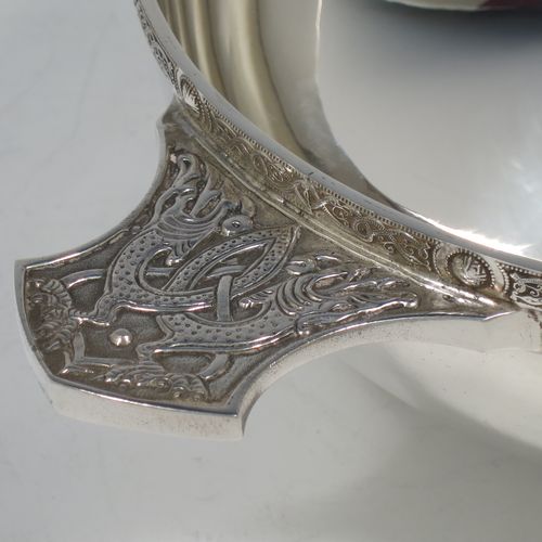 A very handsome and large Sterling Silver Celtic style Quaich, having a very plain round body, with two cast side handles in a Celtic or Cymmric style, a matching applied border, and sitting on a collet foot. This elegant silver Quaich was made by Wakely & Wheeler of London in 1990. The dimensions of this fine hand-made silver Celtic Quaich are diameter of body 16 cms (6.25 inches), height 6 cms (2.3 inches), and it weighs approx. 336g (11.5 troy ounces).    