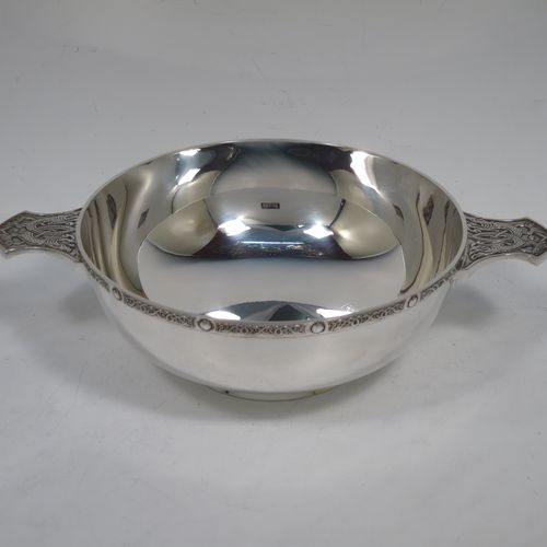 A very handsome and large Sterling Silver Celtic style Quaich, having a very plain round body, with two cast side handles in a Celtic or Cymmric style, a matching applied border, and sitting on a collet foot. This elegant silver Quaich was made by Wakely & Wheeler of London in 1990. The dimensions of this fine hand-made silver Celtic Quaich are diameter of body 16 cms (6.25 inches), height 6 cms (2.3 inches), and it weighs approx. 336g (11.5 troy ounces).    