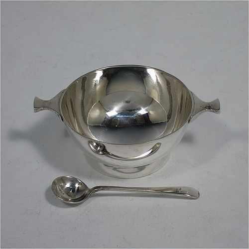 A handsome pair of Scottish Sterling Silver small quaichs, having very plain round bodies, with two side handles, and sitting on collet feet, together with two matching sterling silver Old English pattern spoons. All in their original cream satin and blue velvet-lined presentation box. The quaichs made by Wilson and Sharp of Edinburgh in 1921. The dimensions of these fine hand-made silver quaichs are diameter of body 5.5 cms (2.25 inches), height 2.5 cms (1 inch), and they weigh a total of approx. 90g (3 troy ounces).    