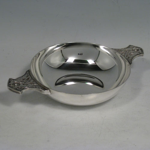 Sterling silver quaich, having a very plain round body, with two side handles having applied Cymric style inter-twined wyverns, and sitting on a collet foot. Made by Wakeley and Wheeler of London in 1944. Diameter of body 11.5 cms (4.5 inches), height 3 cms (1.25 inches). Weight approx. 163g (5.3 troy ounces).