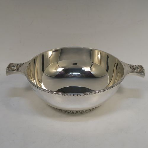 A very handsome, large, and heavy Sterling Silver Celtic style quaich, having a very plain round body, with two cast side handles in a Celtic or Cymmric style, a matching applied border, and sitting on a collet foot. This beautiful silver quaich bowl was made by Henry Atkins of Sheffield in 1938. The dimensions of this fine hand-made silver Celtic style silver quaich are diameter of body 19 cms (7.5 inches), height 7 cms (2.75 inches), and it weighs approx. 670g (21.6 troy ounces).