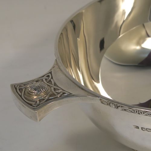 A very handsome, large, and heavy Sterling Silver Celtic style quaich, having a very plain round body, with two cast side handles in a Celtic or Cymmric style, a matching applied border, and sitting on a collet foot. This beautiful silver quaich bowl was made by Henry Atkins of Sheffield in 1938. The dimensions of this fine hand-made silver Celtic style silver quaich are diameter of body 19 cms (7.5 inches), height 7 cms (2.75 inches), and it weighs approx. 670g (21.6 troy ounces).