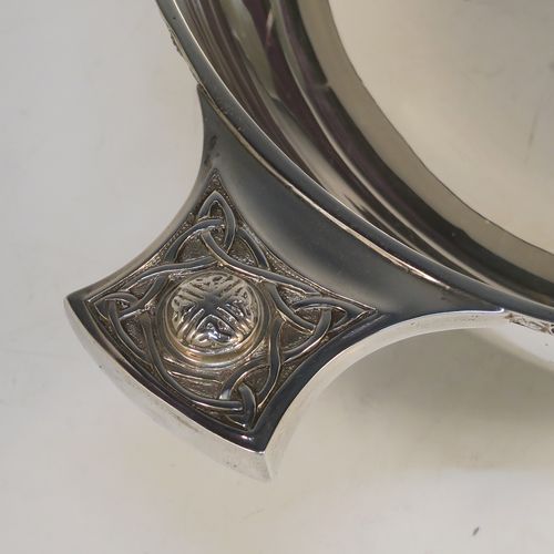 A very handsome, large, and heavy Sterling Silver Celtic style quaich, having a very plain round body, with two cast side handles in a Celtic or Cymmric style, a matching applied border, and sitting on a collet foot. This beautiful silver quaich bowl was made by Henry Atkins of Sheffield in 1938. The dimensions of this fine hand-made silver Celtic style silver quaich are diameter of body 19 cms (7.5 inches), height 7 cms (2.75 inches), and it weighs approx. 670g (21.6 troy ounces).