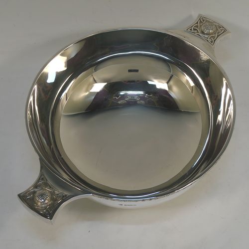 A very handsome, large, and heavy Sterling Silver Celtic style quaich, having a very plain round body, with two cast side handles in a Celtic or Cymmric style, a matching applied border, and sitting on a collet foot. This beautiful silver quaich bowl was made by Henry Atkins of Sheffield in 1938. The dimensions of this fine hand-made silver Celtic style silver quaich are diameter of body 19 cms (7.5 inches), height 7 cms (2.75 inches), and it weighs approx. 670g (21.6 troy ounces).