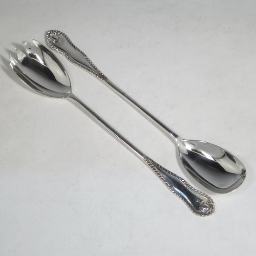 Sterling silver pair of salad servers, having very plain oval bowls, featuring long handles with hand-chased shaped gadroon an floral terminals. Made by Goldsmiths and Silversmiths of Sheffield in 1920. The length of these fine hand-made silver salad servers are 28 cms (11 inches), and the total weight is approx. 196g (6.3 troy ounces).   