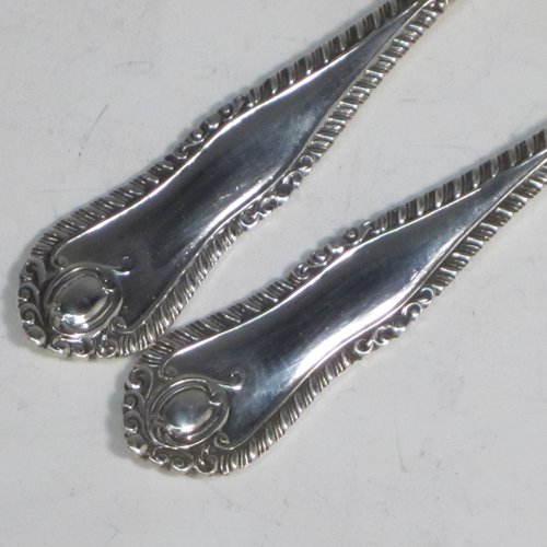 Sterling silver pair of salad servers, having very plain oval bowls, featuring long handles with hand-chased shaped gadroon an floral terminals. Made by Goldsmiths and Silversmiths of Sheffield in 1920. The length of these fine hand-made silver salad servers are 28 cms (11 inches), and the total weight is approx. 196g (6.3 troy ounces).   