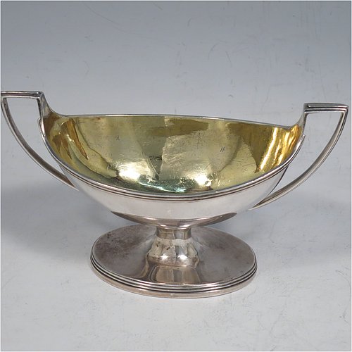 An Antique Georgian Sterling Silver pair of salt cellars, in a boat-shaped style, having plain oval bodies, with gold-gilt interiors, applied reeded borders, and reeded side-handles, all sitting on pedestal feet. Made by either Henry Nutting OR Hannah Northcote of London in 1803. The dimensions of these fine hand-made antique silver salt cellars are length 14 cms (5.5 inches), width 6 cms (2.3 inches), height 7.5 cms (3 inches), and they weigh a total of approx. 217g (7 troy ounces).    