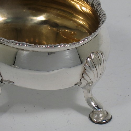 An Antique Georgian Sterling Silver pair of salt cellars, having plain oval bodies, with gold-gilt interiors, applied shaped gadroon borders, and all sitting on four cast hoof feet with shell shoulders. Made by Robert and David Hennell of London in 1767. The dimensions of these fine hand-made antique silver salt cellars are length 9 cms (3.5 inches), width 8 cms (3 inches), height 4.5 cms (1.75 inches), and they weigh a total of approx. 177g (5.7 troy ounces).   