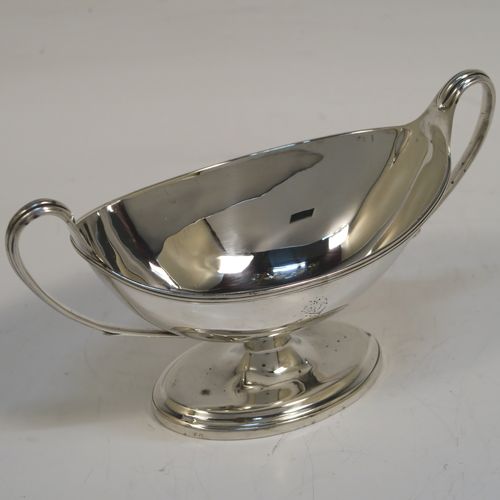 A very handsome Antique Georgian Sterling Silver pair of salt cellars, in a boat-shaped neoclassical style, having plain oval bodies, with blue-glass liners, applied reeded borders, and reeded side-handles, all sitting on pedestal feet. These elegant antique silver salt cellars were made by William Frisbee of London in 1792. The dimensions of these fine hand-made antique silver salt cellars are length 13.5 cms (5.3 inches), width 6 cms (2.3 inches), height 8 cms (3.25 inches), and they weigh a total of approx. 180g (5.8 troy ounces). Please note that both salt cellars have engraved crests.   