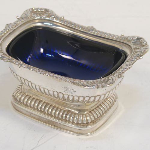 A large and handsome pair of Antique Georgian Sterling Silver salt cellars in a Regency style, having rectangular bodies, with blue-glass liners, applied shell and gadroon borders, half-fluted hand-chased decoration, and all sitting on pedestal bases. These elegant antique silver salt cellars were made in London in 1811. The dimensions of these fine hand-made antique silver salt cellars are length 9.5 cms (3.75 inches), width 7 cms (2.75 inches), height 5 cms (2 inches), and they weigh a total of approx. 237g (7.6 troy ounces). Please note that these items are part crested.   