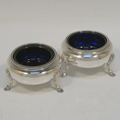 A large and pretty pair of Antique Victorian Sterling Silver cauldron salt cellars, having round bellied bodies with applied bead-edged borders, blue glass liners, and sitting on three cast hoof feet with shell shoulders. These beautiful antique silver salt cellars were made by Arthur Sibley of London in 1862. The dimensions of these fine hand-made antique silver salt cellars are diameter 7 cms (2.75 inches), height 4 cms (1.5 inches), and they weigh a total of approx. 136g (4.4 troy ounces).   