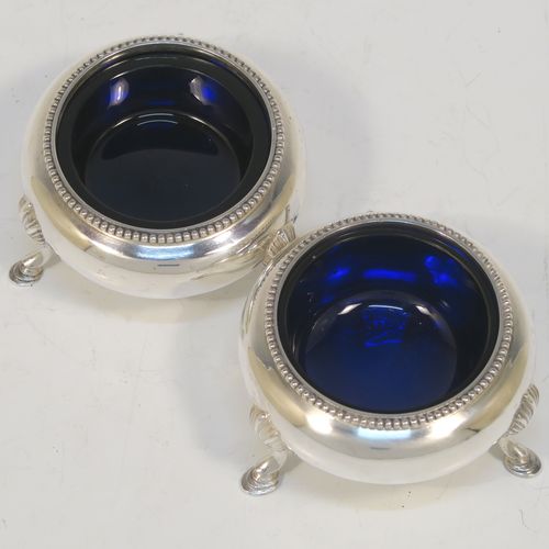 A large and pretty pair of Antique Victorian Sterling Silver cauldron salt cellars, having round bellied bodies with applied bead-edged borders, blue glass liners, and sitting on three cast hoof feet with shell shoulders. These beautiful antique silver salt cellars were made by Arthur Sibley of London in 1862. The dimensions of these fine hand-made antique silver salt cellars are diameter 7 cms (2.75 inches), height 4 cms (1.5 inches), and they weigh a total of approx. 136g (4.4 troy ounces).   