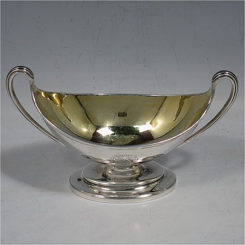 An Antique Georgian Sterling Silver pair of salt cellars, in a boat-shaped neoclassical style, having plain oval bodies, with gold-gilt interiors, applied reeded borders, and reeded side-handles, all sitting on pedestal feet. Made by John Wakelin and William Taylor of London in 1785 (having the rare Incuse duty mark). The dimensions of these fine hand-made antique silver salt cellars are length 13.5 cms (5.3 inches), width 6.5 cms (2.5 inches), height 8 cms (3.25 inches), and they weigh a total of approx. 214g (6.9 troy ounces). Please note that both salt cellars have engraved crests.