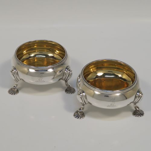 A large and handsome pair of Antique Victorian Sterling Silver salt cellars, having plain round bellied bodies, with gold-gilt interiors, applied shaped bead-edged top borders, and all sitting on three cast shell feet with reeded shoulders. These elegant silver salt cellars were made by Alfred Ivory of London in 1861. The dimensions of these fine hand-made antique silver salt cellars are diameter 7.5 cms (3 inches), height 4 cms (1.5 inches), and they weigh a total of approx. 155g (5 troy ounces). Please note that these items are crested.   