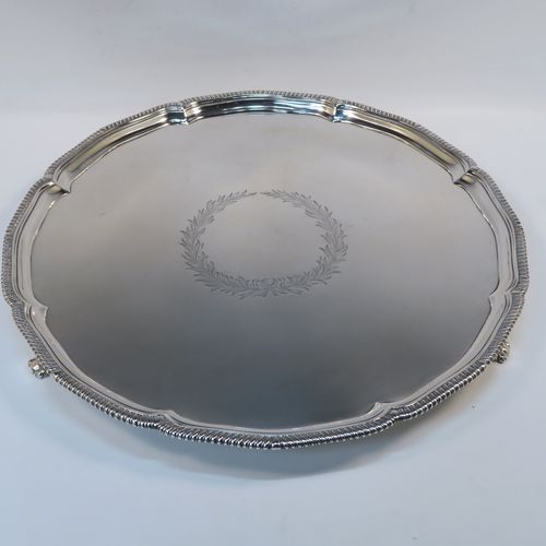 A very elegant Antique Georgian Sterling Silver salver, having an applied shaped gadroon border, a plain ground with a central laurel leaf cartouche., and sitting on three cast scroll and shell feet. This beautiful antique silver salver was made by Hanham and Crouch of London in 1801. The dimensions of this fine hand-made silver salver are diameter 37 cms (14.5 inches), and it weighs approx. 1,288g (41.5 troy ounces).   