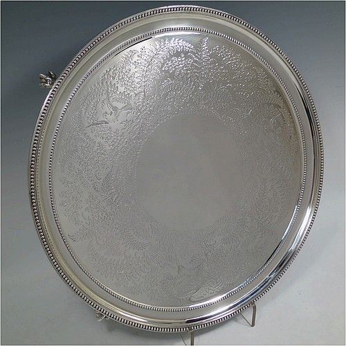 A very pretty Antique Victorian Sterling Silver large salver, having an applied double bead-edged border, with a ground having hand-engraved ferns and song-bird decoration surrounding a central vacant round cartouche, and all sitting on four cast claw and ball feet. Made by Johnson, Walker, and Tolhurst of London in 1881. The dimensions of this fine hand-made antique silver salver are diameter 38 cms (15 inches), and it weighs approx. 1,615g (52 troy ounces).   