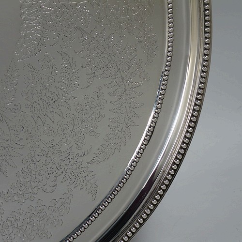 A very pretty Antique Victorian Sterling Silver large salver, having an applied double bead-edged border, with a ground having hand-engraved ferns and song-bird decoration surrounding a central vacant round cartouche, and all sitting on four cast claw and ball feet. Made by Johnson, Walker, and Tolhurst of London in 1881. The dimensions of this fine hand-made antique silver salver are diameter 38 cms (15 inches), and it weighs approx. 1,615g (52 troy ounces).   