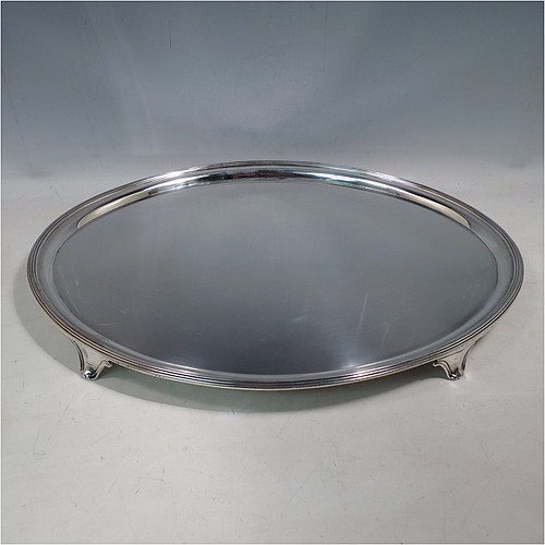 A large Antique Georgian Sterling Silver salver, having an oval body, with a plain burnished ground, an applied Reeded border, and sitting on four cast scroll feet. Made by William Bennett (Possibly) of London in 1801. The dimensions of this fine hand-made silver salver are length 46 cms (18 inches), width 35 cms (13.75 inches), and it weighs approx. 1,735g (56 troy ounces).    