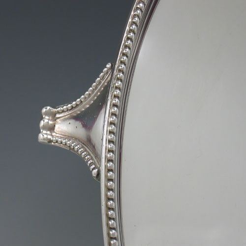 Antique Georgian sterling silver salver, having an applied bead border, plain ground, and sitting on four flange feet with bead edges. Made by Elizabeth Jones of London in 1790. Diameter 36 cms (14 inches). Weight approx. 1,248g (40.3 troy ounces).