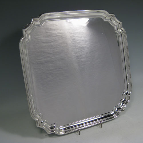    Sterling silver salver, having cut-corners with reeded borders, a plain ground, and sitting on four cast flange feet. Made by William Hutton and Sons of Sheffield in 1944. Dimensions 30 cms (12 inches) square. Weight approx. 1,082g (35 troy ounces).